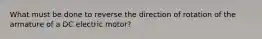 What must be done to reverse the direction of rotation of the armature of a DC electric motor?