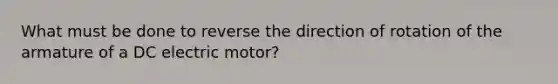 What must be done to reverse the direction of rotation of the armature of a DC electric motor?