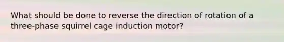 What should be done to reverse the direction of rotation of a three-phase squirrel cage induction motor?