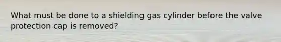 What must be done to a shielding gas cylinder before the valve protection cap is removed?