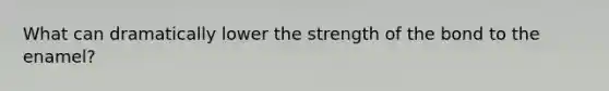 What can dramatically lower the strength of the bond to the enamel?