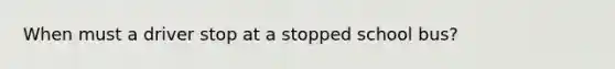 When must a driver stop at a stopped school bus?