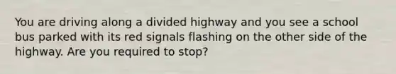 You are driving along a divided highway and you see a school bus parked with its red signals flashing on the other side of the highway. Are you required to stop?