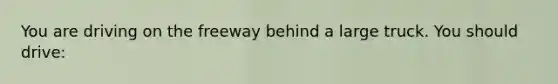 You are driving on the freeway behind a large truck. You should drive: