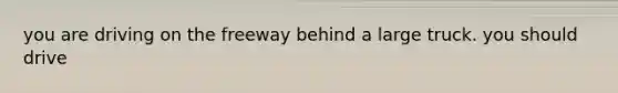 you are driving on the freeway behind a large truck. you should drive