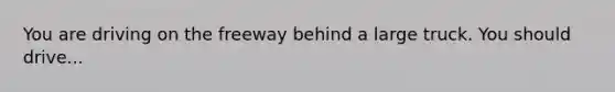 You are driving on the freeway behind a large truck. You should drive...
