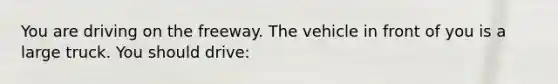 You are driving on the freeway. The vehicle in front of you is a large truck. You should drive: