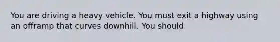 You are driving a heavy vehicle. You must exit a highway using an offramp that curves downhill. You should