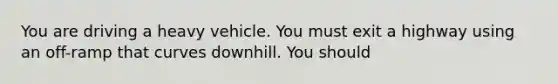 You are driving a heavy vehicle. You must exit a highway using an off-ramp that curves downhill. You should