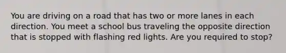 You are driving on a road that has two or more lanes in each direction. You meet a school bus traveling the opposite direction that is stopped with flashing red lights. Are you required to stop?