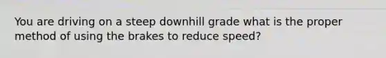 You are driving on a steep downhill grade what is the proper method of using the brakes to reduce speed?