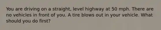 You are driving on a straight, level highway at 50 mph. There are no vehicles in front of you. A tire blows out in your vehicle. What should you do first?