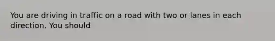 You are driving in traffic on a road with two or lanes in each direction. You should