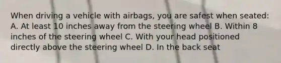 When driving a vehicle with airbags, you are safest when seated: A. At least 10 inches away from the steering wheel B. Within 8 inches of the steering wheel C. With your head positioned directly above the steering wheel D. In the back seat