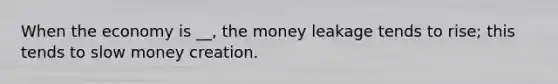 When the economy is __, the money leakage tends to rise; this tends to slow money creation.