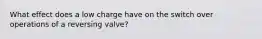 What effect does a low charge have on the switch over operations of a reversing valve?