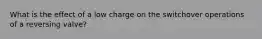 What is the effect of a low charge on the switchover operations of a reversing valve?