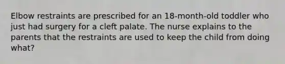 Elbow restraints are prescribed for an 18-month-old toddler who just had surgery for a cleft palate. The nurse explains to the parents that the restraints are used to keep the child from doing what?