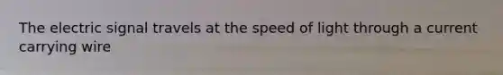 The electric signal travels at the speed of light through a current carrying wire