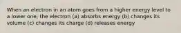When an electron in an atom goes from a higher energy level to a lower one, the electron (a) absorbs energy (b) changes its volume (c) changes its charge (d) releases energy