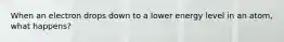 When an electron drops down to a lower energy level in an atom, what happens?
