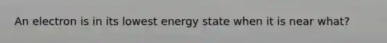 An electron is in its lowest energy state when it is near what?