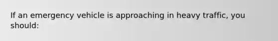 If an emergency vehicle is approaching in heavy traffic, you should:
