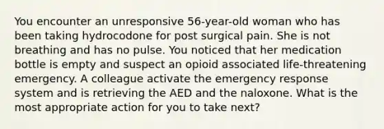 You encounter an unresponsive 56-year-old woman who has been taking hydrocodone for post surgical pain. She is not breathing and has no pulse. You noticed that her medication bottle is empty and suspect an opioid associated life-threatening emergency. A colleague activate the emergency response system and is retrieving the AED and the naloxone. What is the most appropriate action for you to take next?