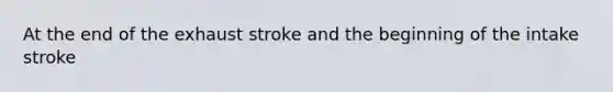 At the end of the exhaust stroke and the beginning of the intake stroke