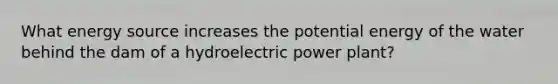 What energy source increases the potential energy of the water behind the dam of a hydroelectric power plant?