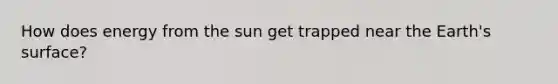 How does energy from the sun get trapped near the Earth's surface?