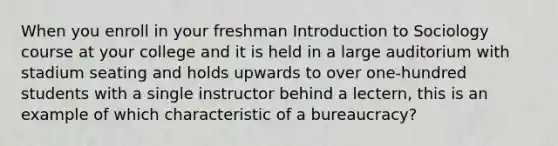 When you enroll in your freshman Introduction to Sociology course at your college and it is held in a large auditorium with stadium seating and holds upwards to over one-hundred students with a single instructor behind a lectern, this is an example of which characteristic of a bureaucracy?