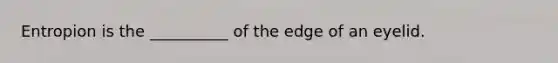 Entropion is the __________ of the edge of an eyelid.