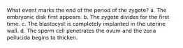 What event marks the end of the period of the zygote? a. The embryonic disk first appears. b. The zygote divides for the first time. c. The blastocyst is completely implanted in the uterine wall. d. The sperm cell penetrates the ovum and the zona pellucida begins to thicken.