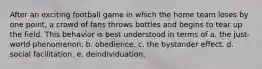 After an exciting football game in which the home team loses by one point, a crowd of fans throws bottles and begins to tear up the field. This behavior is best understood in terms of a. the just-world phenomenon. b. obedience. c. the bystander effect. d. social facilitation. e. deindividuation.