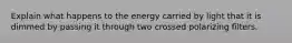 Explain what happens to the energy carried by light that it is dimmed by passing it through two crossed polarizing filters.