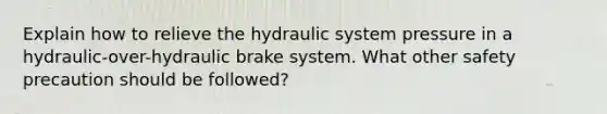 Explain how to relieve the hydraulic system pressure in a hydraulic-over-hydraulic brake system. What other safety precaution should be followed?