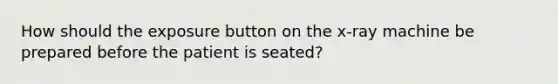 How should the exposure button on the x-ray machine be prepared before the patient is seated?