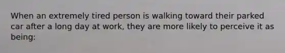 When an extremely tired person is walking toward their parked car after a long day at work, they are more likely to perceive it as being: