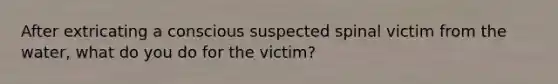 After extricating a conscious suspected spinal victim from the water, what do you do for the victim?