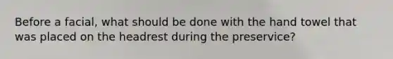 Before a facial, what should be done with the hand towel that was placed on the headrest during the preservice?