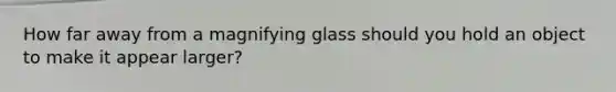 How far away from a magnifying glass should you hold an object to make it appear larger?