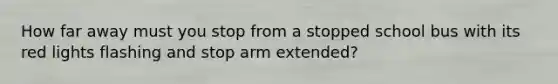 How far away must you stop from a stopped school bus with its red lights flashing and stop arm extended?