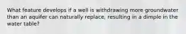 What feature develops if a well is withdrawing more groundwater than an aquifer can naturally replace, resulting in a dimple in the water table?