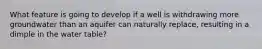 What feature is going to develop if a well is withdrawing more groundwater than an aquifer can naturally replace, resulting in a dimple in the water table?