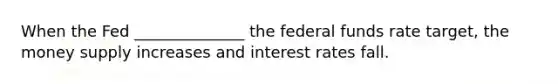 When the Fed ______________ the federal funds rate target, the money supply increases and interest rates fall.