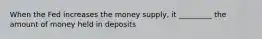 When the Fed increases the money supply, it _________ the amount of money held in deposits