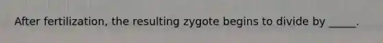 After fertilization, the resulting zygote begins to divide by _____.