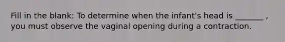 Fill in the blank: To determine when the infant's head is _______ , you must observe the vaginal opening during a contraction.