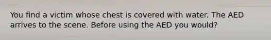 You find a victim whose chest is covered with water. The AED arrives to the scene. Before using the AED you would?